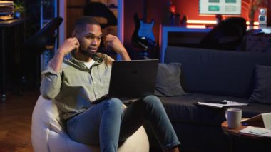 Siyahi biri kulaklıklarla müzik dinleyip işlerini bitiriyor. Oturma odasında fasulye torbasının üzerinde birden fazla iş yapıyor. Sakin çalışmanın tadını çıkaran genç yetişkinler görevlerini tamamlıyor. Kamera B.