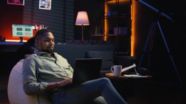 Ürün ve hizmetler hakkında stratejik tavsiyelerde bulunmak için aylık bütçeyi ve harcamaları inceleyen analist. Zenci genç iş adamı gelir dengesi analizi yapıyor, evde muhasebe yapıyor. Kamera A.