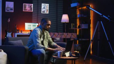 Uzaktan kumandalı bilgisayarla çalışan Afro-Amerikalı genç bir yetişkin çatı katı ışıklarının altında, rahat dairesinde bir kanepede oturuyor. Şık bir evde rahat bir insan modern üretkenliği ön plana çıkarıyor. Kamera A.