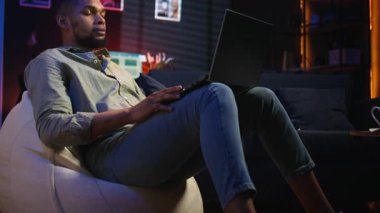 Siyah erkek serbest çalışan evden yeni beceriler öğrenmek için online kursa katılıyor, çevrimiçi video görüşmelerine katılıyor ve tavan arasından ders seyrediyor. Genç adam sanal eğitim sınıfına katılıyor. Kamera A.