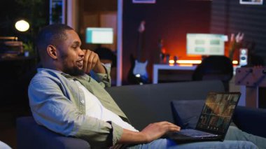 Gülümseyen Afro-Amerikalı bir adam sanal aile toplantısını internet üzerinden sunuyor, akrabalarıyla görüşüyor ve son haberleri paylaşıyor. Adam sohbet etmek için web bağlantısını kullanıyor. Kamera A.