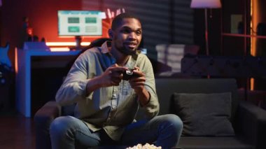 POV genç siyahi yetişkin akıllı TV 'de atış oyunu oynayarak, oturma odasında konsol takarak ve geceleri oyun oynayarak eğleniyor. Eğlenceli aktiviteler yapan bir adam. Kamera B.