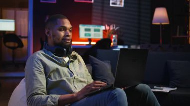 Siyahi biri kulaklıklarla müzik dinleyip işlerini bitiriyor. Oturma odasında fasulye torbasının üzerinde birden fazla iş yapıyor. Sakin çalışmanın tadını çıkaran genç yetişkinler görevlerini tamamlıyor. Kamera A.