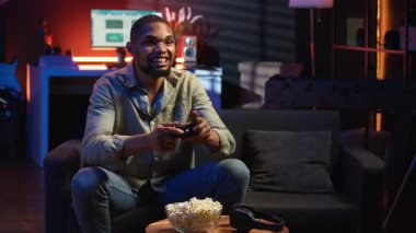 Neşeli, kendine güvenen, video oyunları şampiyonluğunu kazanan, başarısını kutlayan ve bundan memnun olan kişi. Keyifli siyahi adam boş zamanın tadını çıkarıyor ve oyun kazanıyor. Kamera B.