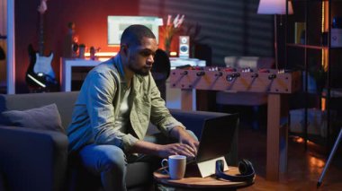 Uzaktan kumandalı bilgisayarla çalışan Afro-Amerikalı genç bir yetişkin çatı katı ışıklarının altında, rahat dairesinde bir kanepede oturuyor. Şık bir evde rahat bir insan modern üretkenliği ön plana çıkarıyor. Kamera B.