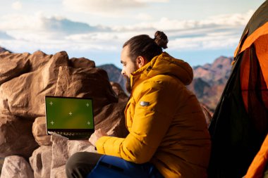 Trekker, sakin dağ manzarası ve açık gökyüzünün macerayı ve azmi simgelediği izole edilmiş taklit ekranın yanındaki panoramik manzarayı alıyor. Teknolojik seyahat tutkusu.