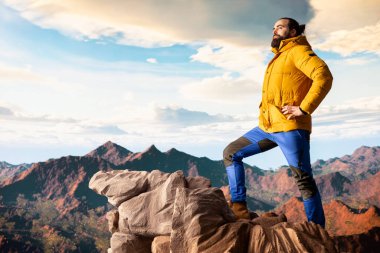 Yürüyüşçü dağların panoramik manzarasına hayran olmak için bir dakikasını ayırır, uzaklığa ve manzaraya bakar. Temiz hava, manzaralı arka plan ve bir kaşif için huzurlu bir ortam..