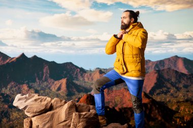 Erkek kaşif yüksek rakımlı vahşi doğanın yalnızlığını kucaklıyor, temiz hava ve manzaralı bir arka plan için dağın tepesine tırmanıyor. Doğadaki farkındalık ve rahatlama.