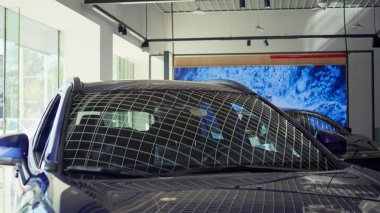 İlgilenen müşteriler tarafından satın alınmayı bekleyen gösterişli tasarımı olan arabaların yakın plan çekimleri. Potansiyel müşteriler için galeride modern araç modelleri tanıtılıyor