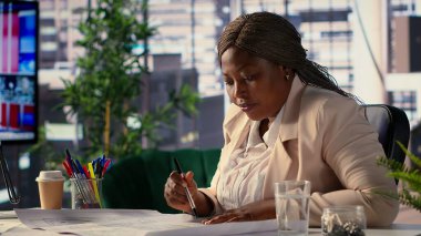 Siyahi kadın yönetmen, yeni ofis planının mimari planlarını değerlendiriyor, girişiminin yerini değiştiriyor. Girişimci, strateji planlaması için bir ofis avı düzenler. Kamera A.