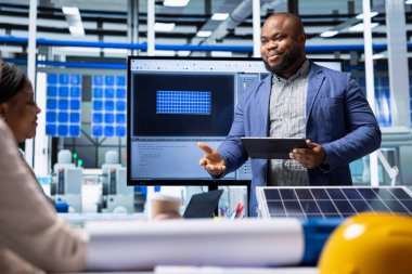 Fotovoltaik fabrikası yöneticileri yenilenebilir enerji üretim makinelerini analiz ediyorlar. Güneş panelleri yatırım kârlılığını değerlendirmek için üretim istatistiklerini inceleyen fabrika yatırımcıları