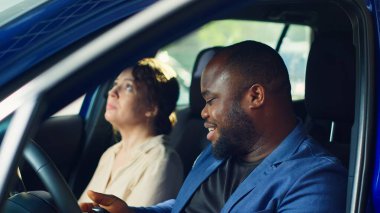 Müşteriler araba almadan önce test sürüşüne çıkıyorlar, pedallardan ve koltuk ayarlarından memnun kaldıktan sonra satıcıdan anahtar alıyorlar. Müşteriler, A kamerasından satın almadan önce aracın hislerini değerlendirir.