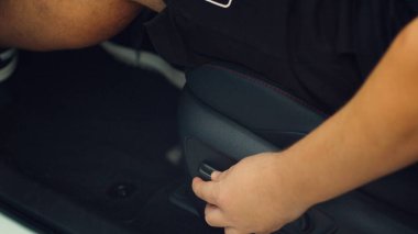 Arabanın şoför koltuğunu düğmelerle ayarlayan adama yaklaş. Sürücünün rahatlığı için yükseltilebilen, alçaltılabilen, eğrilebilen, ileri ve geri hareket edebilen bir araç sandalyesi.
