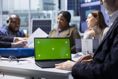 Hissedarlar ve üretim fabrikası yöneticisi yeşil ekran dizüstü bilgisayar kullanarak sürdürülebilir üretim verilerini analiz ediyorlar. Yatırımcılar yatırım kârlılığını değerlendirmek için kroma anahtar defterindeki belgeleri gözden geçirirler