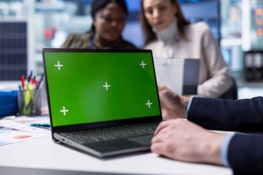 Fabrika çalışanı, güneş paneli otomasyon stratejilerini tartışan yöneticilerin yanındaki yeşil ekranda çalışıyor. Üretim süreçlerini geliştiren ekibin yanındaki deftere yazı yazan işçiler,