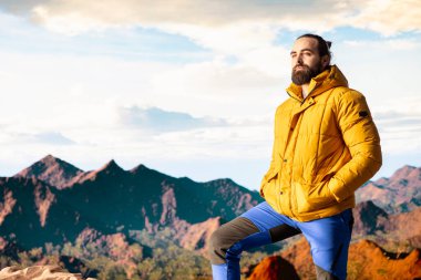 Erkek kaşif yüksek rakımlı vahşi doğanın yalnızlığını kucaklıyor, temiz hava ve manzaralı bir arka plan için dağın tepesine tırmanıyor. Doğadaki farkındalık ve rahatlama.