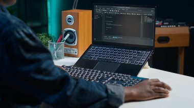 Oturma odasındaki telgraf işçisi yazılım geliştirme ve el kamerası görüntüleri için dizüstü bilgisayar kullanıyor. Aygıt klavyesinde yazan uzaktan çalışan, apartmandaki görevleri çözen, kamera A, kapat