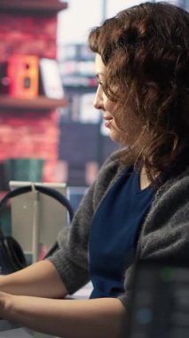 Dikey Video Kadın Sistemi Yöneticisi yapay zeka sistemlerinde bakım yapıyor, ofis masasında oturuyor. Kız, sibernetik ve makine öğrenme algoritmalarında yazılım geliştiricisi olarak çalışıyor. Kamera B.