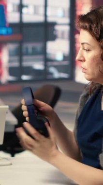 Dikey Video Kadın Tüccar, çift monitörlerdeki borsa grafiklerini inceleyerek, fiyatları paylaşmak için finansal büyümeyi izliyor. Ticaret arayüzü hisse alıp satmak için gerçek zamanlı veri sağlıyor