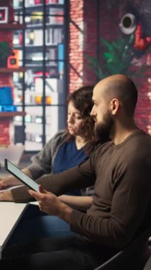 Vertical Video Startup çalışanları iş konferansını PC monitöründen izliyor, defter hakkında bilgi yazıyor ve görüşlerini paylaşıyorlar. Çalışanlar bilgisayardaki sunum grafiklerine bakıyor, notlar alıyorlar