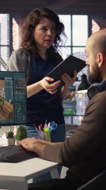 Dikey Video Mimari Tasarım Ekibi çift monitörler üzerinde bilgisayar destekli tasarım araçları kullanarak bir kat planı hazırlar. Meslektaşlar dijital hazırlama ve iç dekorasyon için yazılım kullanırlar