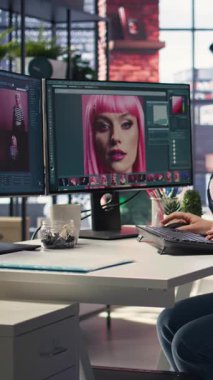 Ajans ofisindeki modern bir bilgisayar kurulumunda resim düzenleyen dikey video fotoğrafçısı renk derecelendirme ve rötuş tekniği kullanıyor. Dijital tasarımcı ve sanat fotoğrafçılığı için ideal bir çalışma alanı. Kamera A.