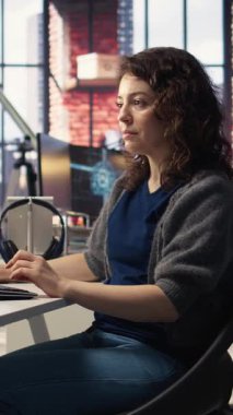 Ofisteki Dikey Video Genç kadın bilgisayar ekranında UI 'ye bakıyor ve yazılımda bir şeyler denemek ve uygulamak için ikili kod çalıştırıyor. Bilgisayar bilimi için kodlama uygulaması. Kamera A