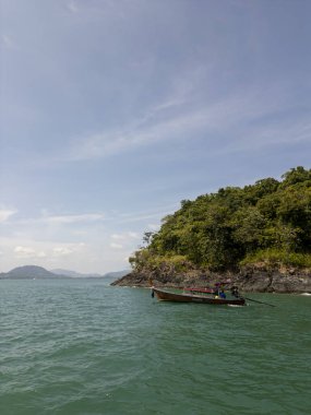 Tropikal plajın ve egzotik palmiyeler ve mavi gökyüzü ile panoramik ormanın insansız hava aracı çekimi, güneşli bir kıyı şeridinde uzun hindistan cevizi ağaçlarının yer aldığı kıyı manzarası. Tayland 'da sakin deniz kıyısı, insansız hava aracı..