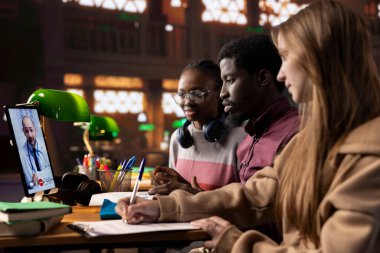 Kütüphanedeki çeşitli akademisyen akademisyenler, bilim, tedavi yöntemleri ve teletıp hakkındaki bilgilerini geliştirmek için bir sıhhiye öğretmeniyle video görüşmesine katılıyorlar. Öğrenciler tıp pratiği dersleri öğrenirler..