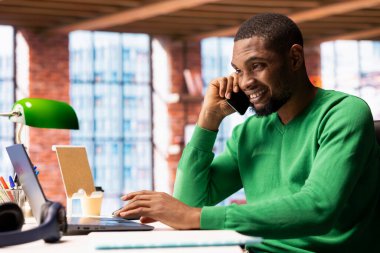 Mutlu bir adam telefonla arkadaşlarıyla dostça sohbet ediyor. Evdeki neşeli insan arkadaşlarıyla sohbet ediyor, cep telefonuyla konuşuyor.