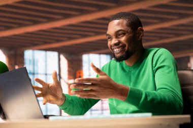 Mutlu adam evde dizüstü bilgisayardan iyi haberler okuyor ve tezahürat yapıyor. Memnuniyetle Afro-Amerikan vatandaşı apartmandaki defter ekranında olumlu bilgiler okuduktan sonra kutlama yapıyor.