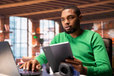 Ofiste e-posta yazmak için bilgisayarını ve tabletini kullanan uzaktan çalışan. Dijital aygıtlar kullanan serbest çalışan, bitirilmiş proje evraklarını teslim etmek için belge düzenleyen