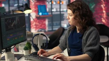 Ajans ofisinde video yapım sektöründe çalışan kadın uzman editör, renk derecelendirme yapıyor ve çift monitörlerde bir montaj yaratıyor. Multimedya teknoloji araçlarıyla yaratıcı bir süreç. Kamera B.