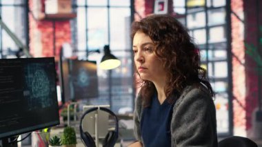 Yapay zeka sistemlerinde bakım yapan kadın bilişim mühendisi ofis masasında oturuyor. Genç kadın sibernetik ve makine öğrenme algoritmalarında geliştirici olarak çalışıyor. Kamera B.