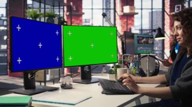 Ofisteki çalışan bilgisayar üzerinde çalışıyor. İkili monitörlerde izole edilmiş bir kopya alanı var. Yaratıcı ajans modern düzeneği. Kadın optimize uzayda grafik tasarım, kodlama veya yapay zeka destekli görevlere odaklanmış. Kamera A.