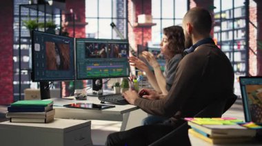 Yapay zeka sohbet robotu ve montaj yapıcı yazılımla çalışan video düzenleme ekibi, arka plan videosu düzenleme ve çift monitörlerde klipleri karıştırma. Yaratıcılık sürecinde olan profesyonel erkek ve kadın. Kamera A.