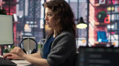 Bilgisayarındaki yazılım kodunu programlayan genç bir kadın görevleri düzeltmek için kodlama dili kullanıyor. Çift monitörlü çalışma alanı yazılım mühendisliği ve web geliştirmesine yardımcı olur. Kamera B.