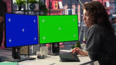 Ofisteki çalışan bilgisayar üzerinde çalışıyor. İkili monitörlerde izole edilmiş bir kopya alanı var. Yaratıcı ajans modern düzeneği. Kadın optimize uzayda grafik tasarım, kodlama veya yapay zeka destekli görevlere odaklanmış. Kamera B.