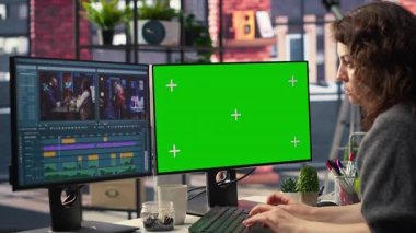 Yeşil ekranın yanında bir film montajı yapan kadın kameraman, çift taraflı monitör kurulumu ve düzenleme yazılımı ile birden fazla iş yapıyor. Sinema endüstrisi için prodüksiyon işlerini bitiriyorum. Kamera B.