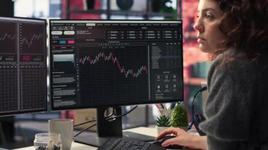 İş kadını, borsa görselleştirme araçlarını kullanarak finansal tablolar üzerinde çalışıyor. Dijital ticaret platformu yatırım planlaması için ekonomik veriler, önx analizleri ve fiyat eğilimleri sunar. Kamera B.