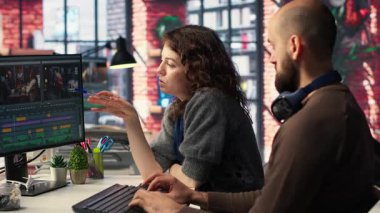 Erkek ve kadın film yapımcıları, modern teknoloji kurulumu ve yaratıcı bir video projesi için kurgu yazılımı kullanarak, post prodüksiyonda video çekimleri düzenliyorlar. Çift monitörlü modern çalışma alanı. Kamera B.