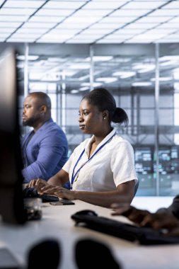 Veri merkezindeki Afrikalı Amerikalı yönetici yüksek işlemci kullanımı nedeniyle PC kullanarak sunucu performans sorunlarını kontrol ediyor. Sunucu merkezindeki kadın yetersiz bellek hatalarını düzelterek donanımı yavaşlatıyor