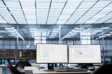 Boş veri merkezinin çalışma alanındaki bilgisayar ekranında çalışan kod, sorun giderme rackmount 'larında kullanılır. Masaüstü bilgisayarında çalışan ikili betik sunucu odasındaki ana bilgisayar sistemlerini yükseltiyor