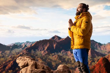 Keyifli bir doğa aşığı dağ sırasının tepesinde meditasyon yapıyor, meditasyon yapıyor ve rahatlık ve zihinsel berraklık için derin nefesler alıyor. Huzurlu zen yürüyüşçüsü tırmanmayı sever.