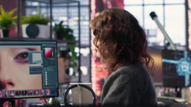 Kadın editör ajanstaki yazılımda renk derecelendirme kullanıyor, profesyonel yüksek kaliteli fotoğraflar üzerinde çalışıyor. Medya içeriği için düzenleme arayüzü ve araçları ile çalışan tasarımcı. Kamera B.