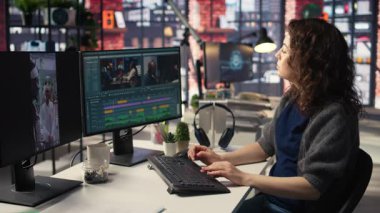 Ajans ofisinde video yapım sektöründe çalışan kadın uzman editör, renk derecelendirme yapıyor ve çift monitörlerde bir montaj yaratıyor. Multimedya teknoloji araçlarıyla yaratıcı bir süreç. Kamera A.