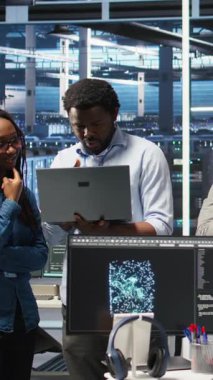 Verileri analiz etmek için düğüm ağacı yazılımı kullanarak sunucu tesisinde işbirliği yapan gülümseyen veri merkezi uzmanlarının dikey video portresi. Mutlu takım vitesi geliştirmek için görsel programlama kullanıyor