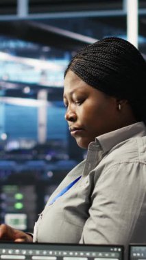 Sistem sağlığını optimize etmek için yapay zeka görüşlerini kullanan neşeli sunucu merkezi teknisyeninin dikey video portresi. Neşeli veri merkezi bilişim uzmanı düğüm ağacı araçları, kamera B kullanarak dişli sorunlarını analiz ediyor