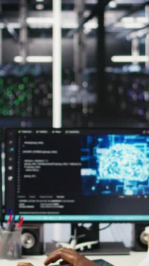 Dikey Veri Merkezi çalışanı mikrofonla konuşuyor, yapay zeka konuşlandırması için donanım kuran teknisyenleri koordine ediyor. Sunucu odası çalışanı uzaktan arama yapıyor