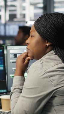 Verileri analiz etmek için yapay zeka algoritmaları kullanan dikey video veri merkezi çalışanı. Sunucu odasında yapay zeka sinirsel ağlar kullanan Afrikalı Amerikalı bir kadın var.